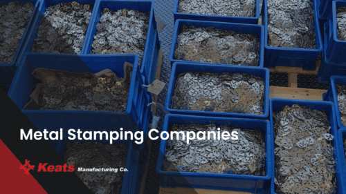 Precision metal stamping parts in blue containers at Keats Manufacturing.